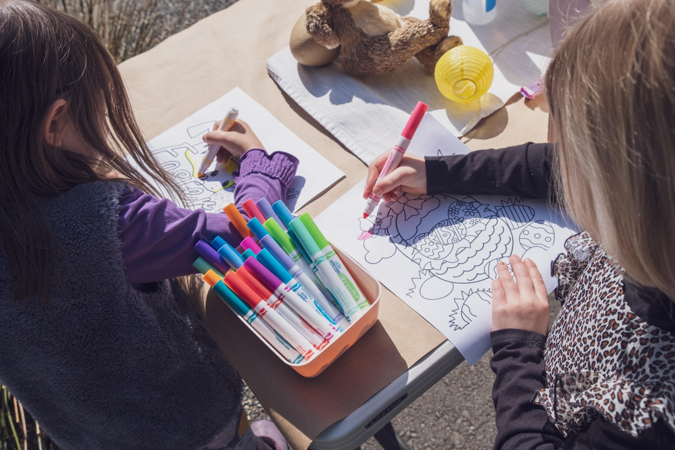 Zwei Kinder malen Bilder mit Ostereiern in bunten Farben