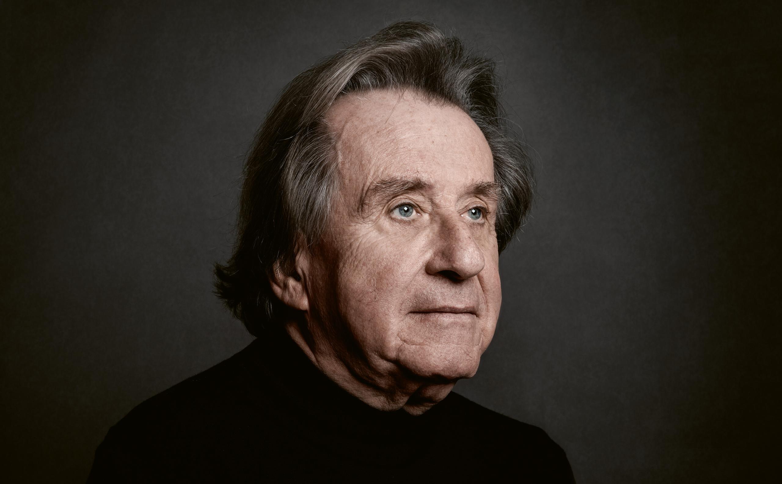 Portrait of the pianist Rudolf Buchbinder. He is seen in side profile and depicted against a dark grey background