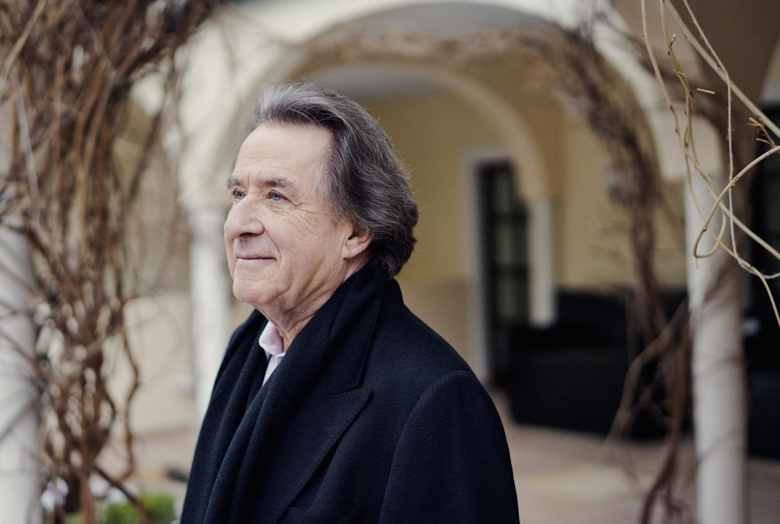 Portrait of the pianist Rudolf Buchbinder. He is standing in a courtyard and can be seen in side profile.