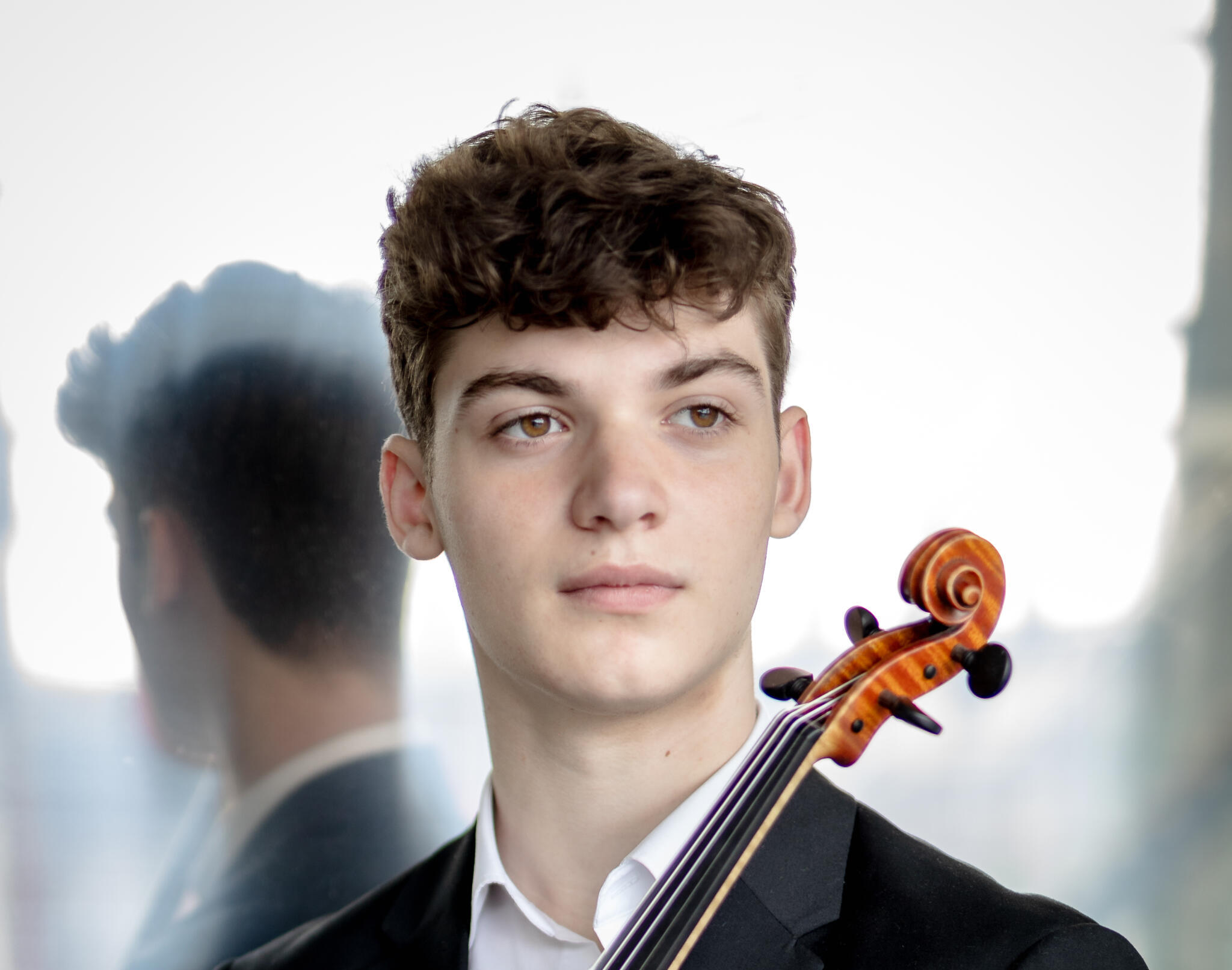 Porträt des Violinisten Andrea Cicalese. Er trägt einen schwarzen Anzug und hält seine Violine in der Hand.