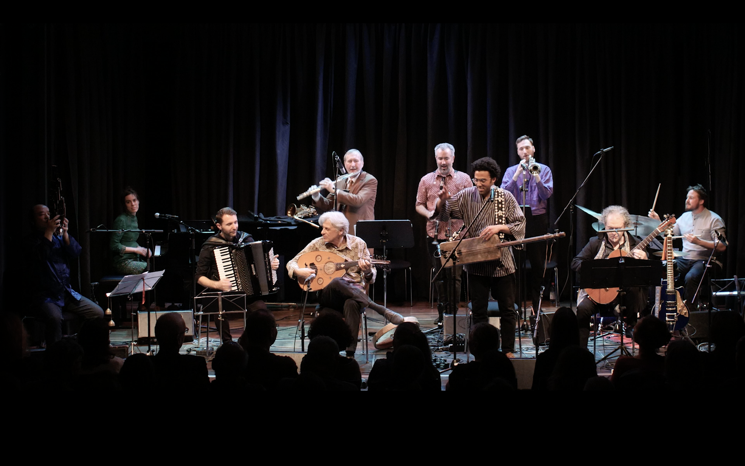 A group of musicians with oriental instruments on a stage.