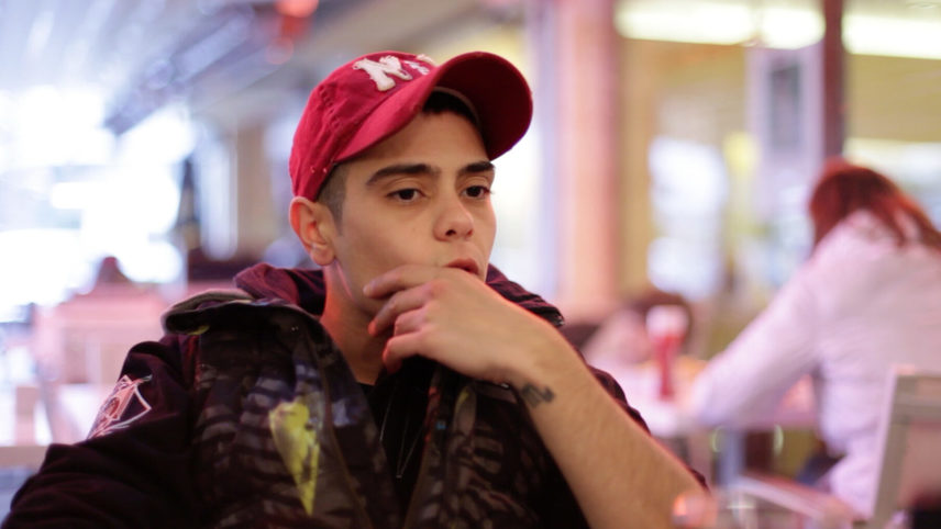 The picture shows a young man with a red cap looking thoughtfully into the distance.