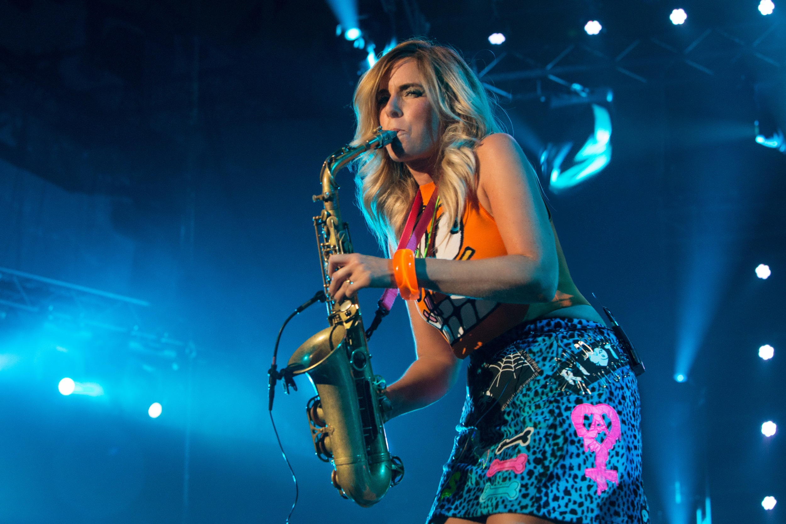 Saxophonist Candy Dulfer plays on a blue-lit stage.
