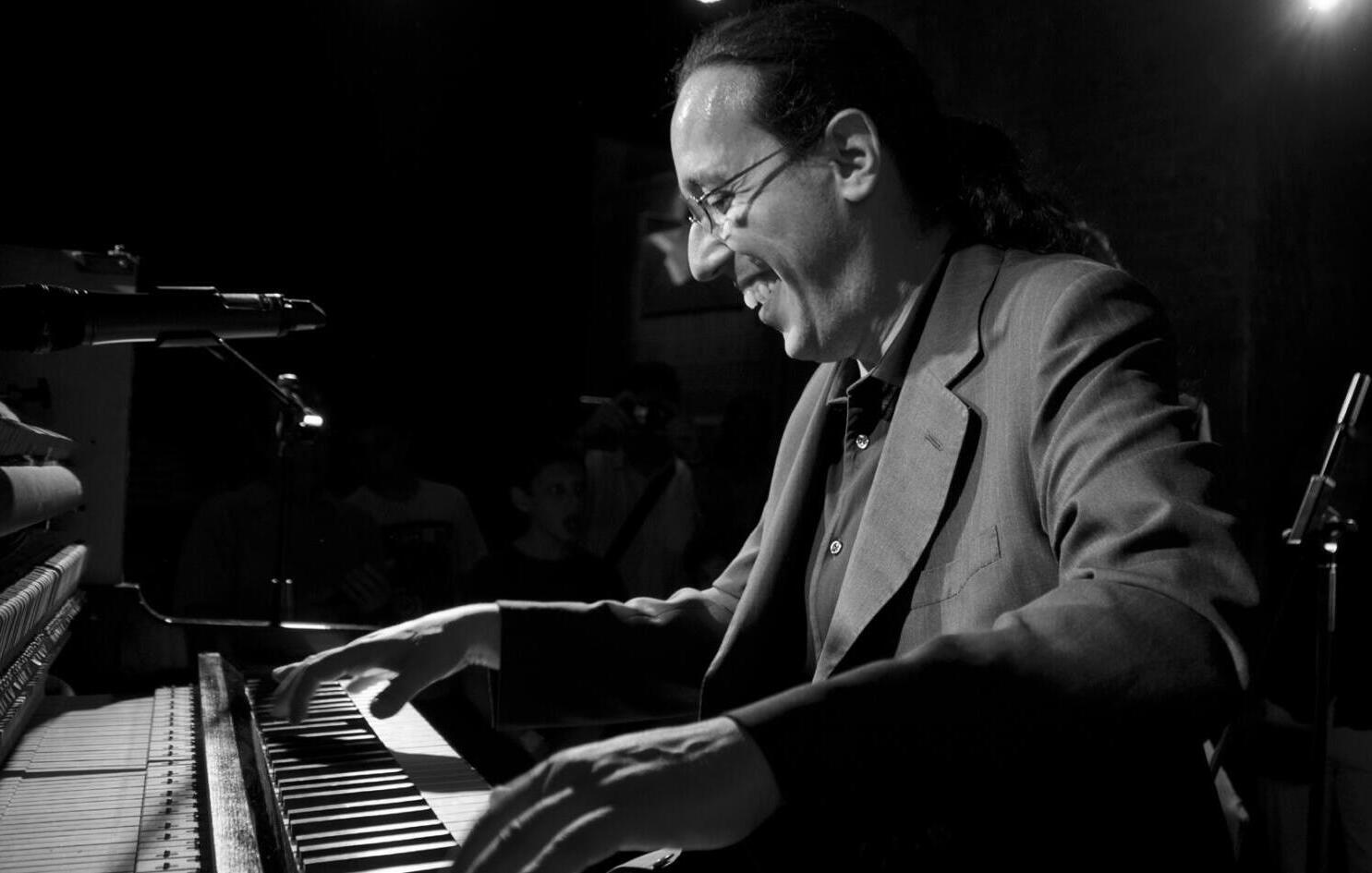 A man plays the piano laughing.
