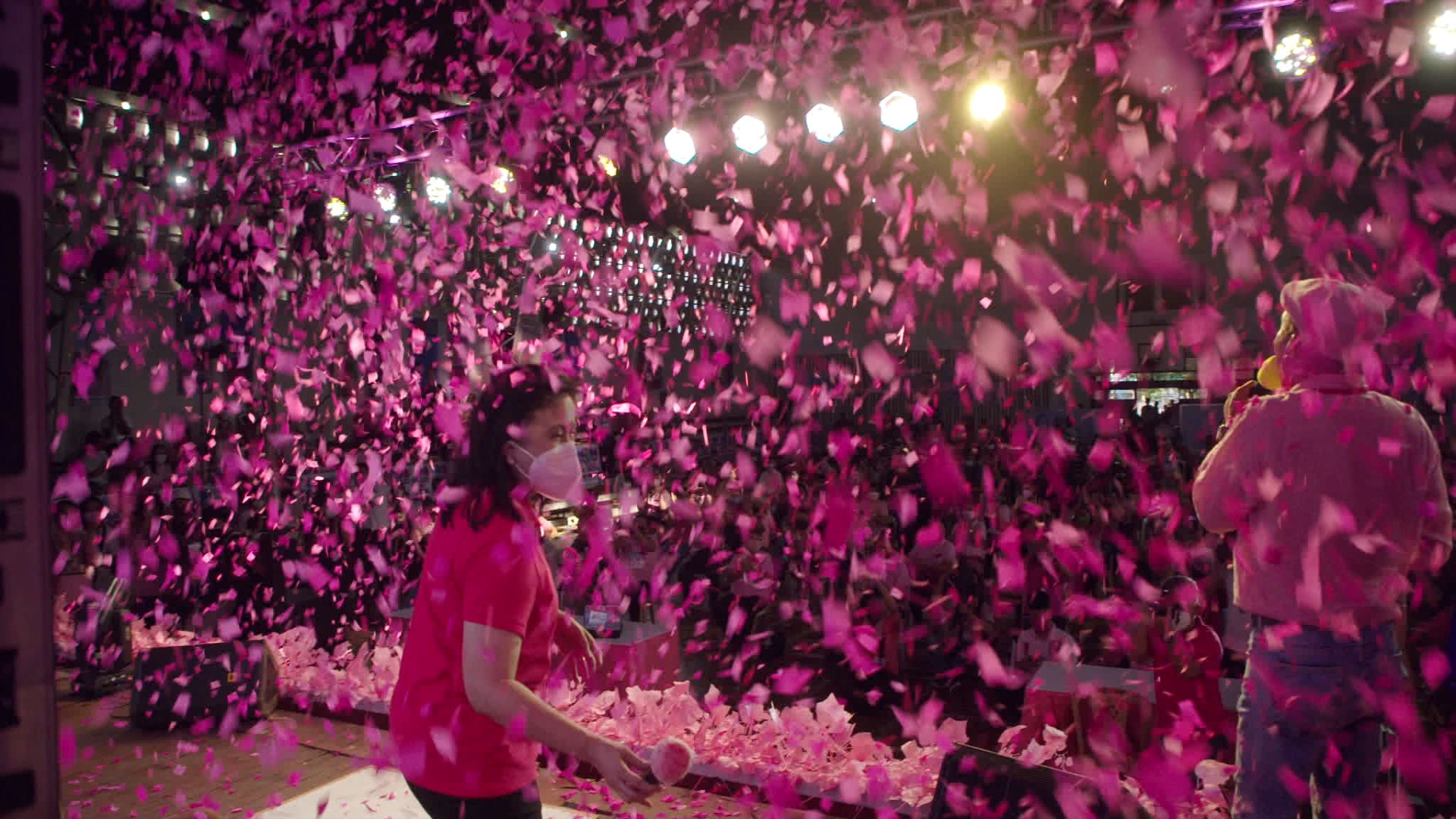 A woman stands on a stage full of pink confetti.
