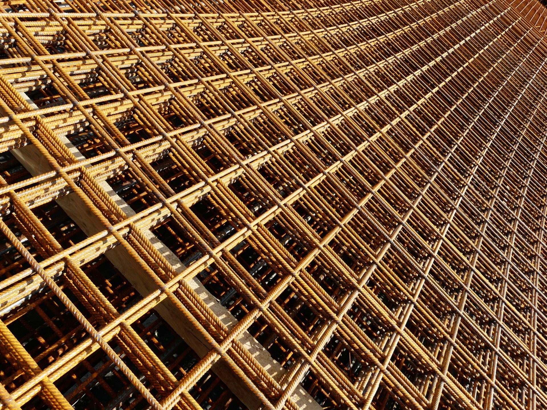 Lange Gerüststangen für ein Bauwerk bilden mit Querstangen ein Muster aus vielen Quadraten.