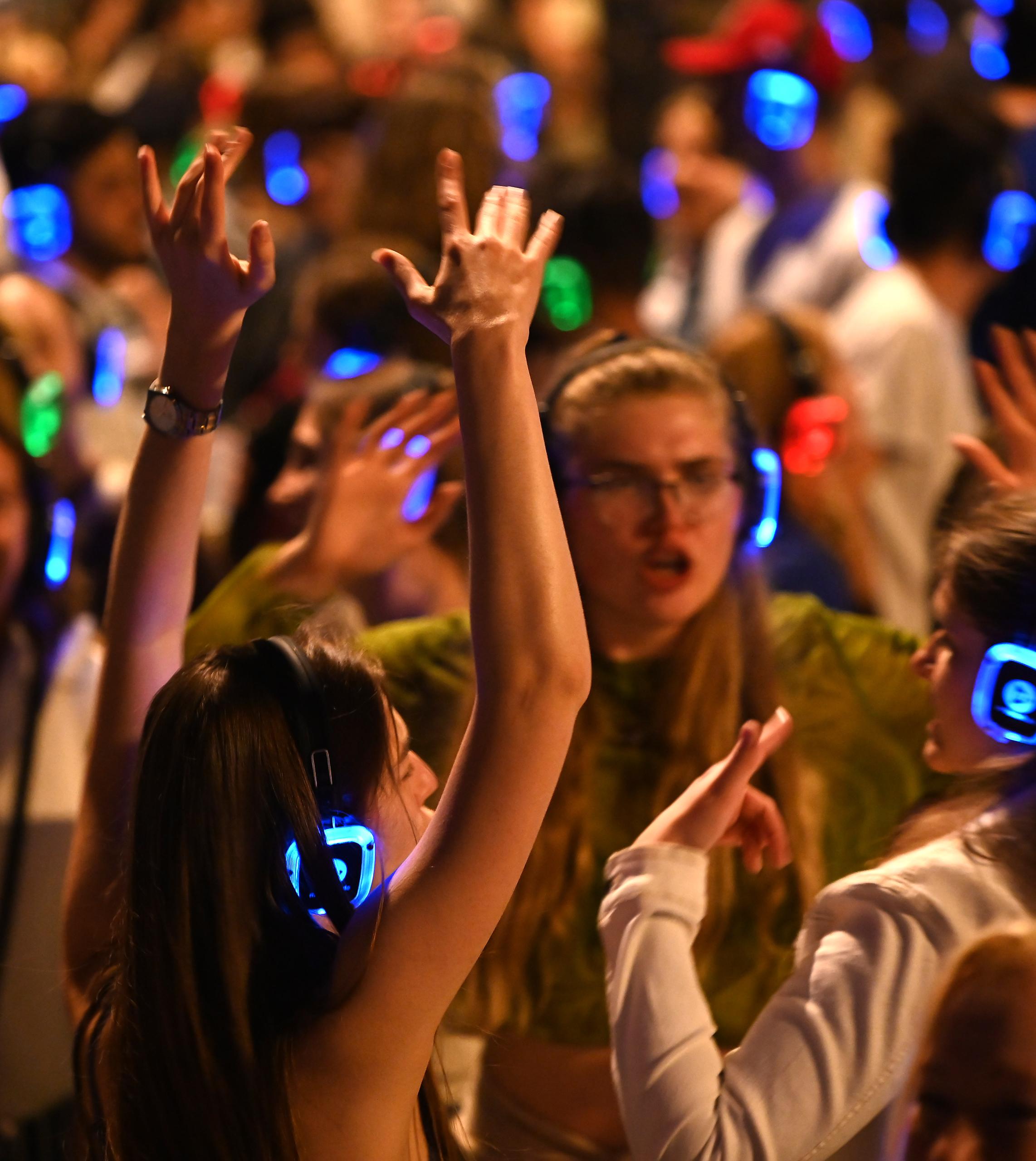 Menschen tanzen mit leuchtenden Kopfhörern