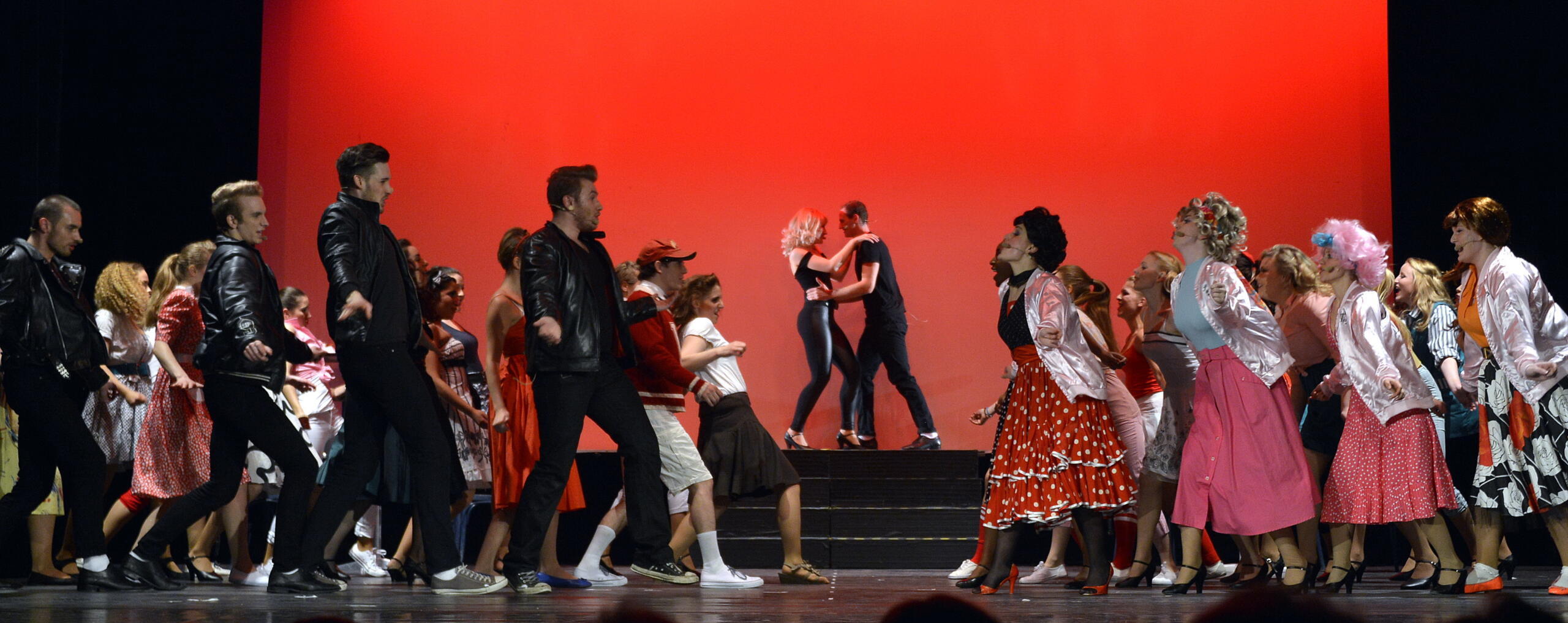 A stage with many dancers in 50s clothing.