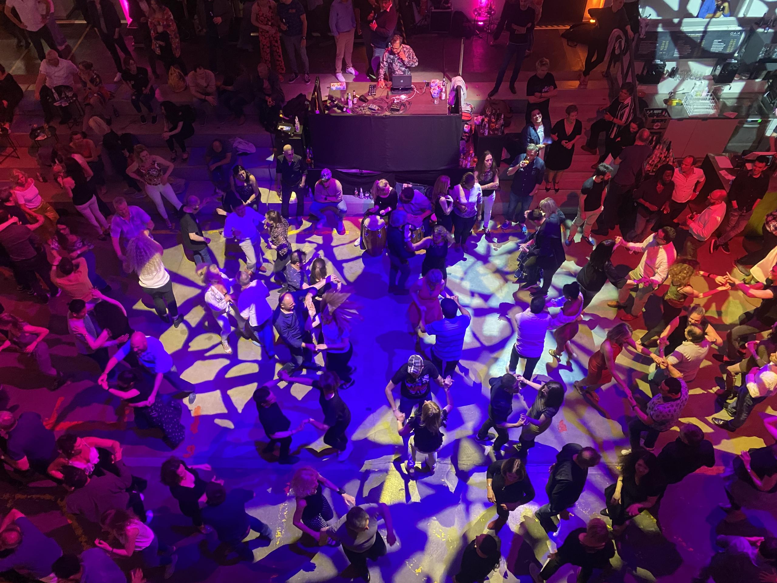 Menschen auf einer bunt beleuchteten Tanzfläche Salsa.
