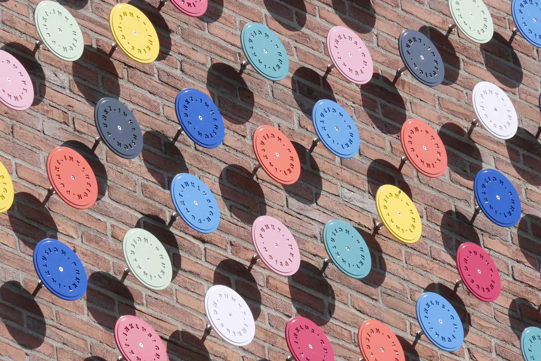 Brick wall on which colourful metal dots with the writing Inclusion Point are placed