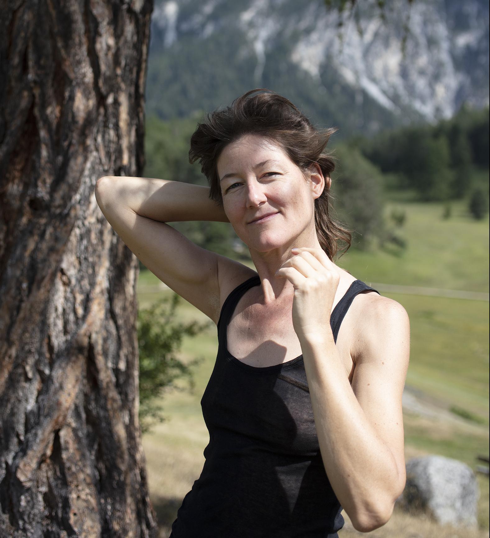 Porträt der Comiczeichnerin Lika Nüssli, wie sie an einem Baum lehnt.