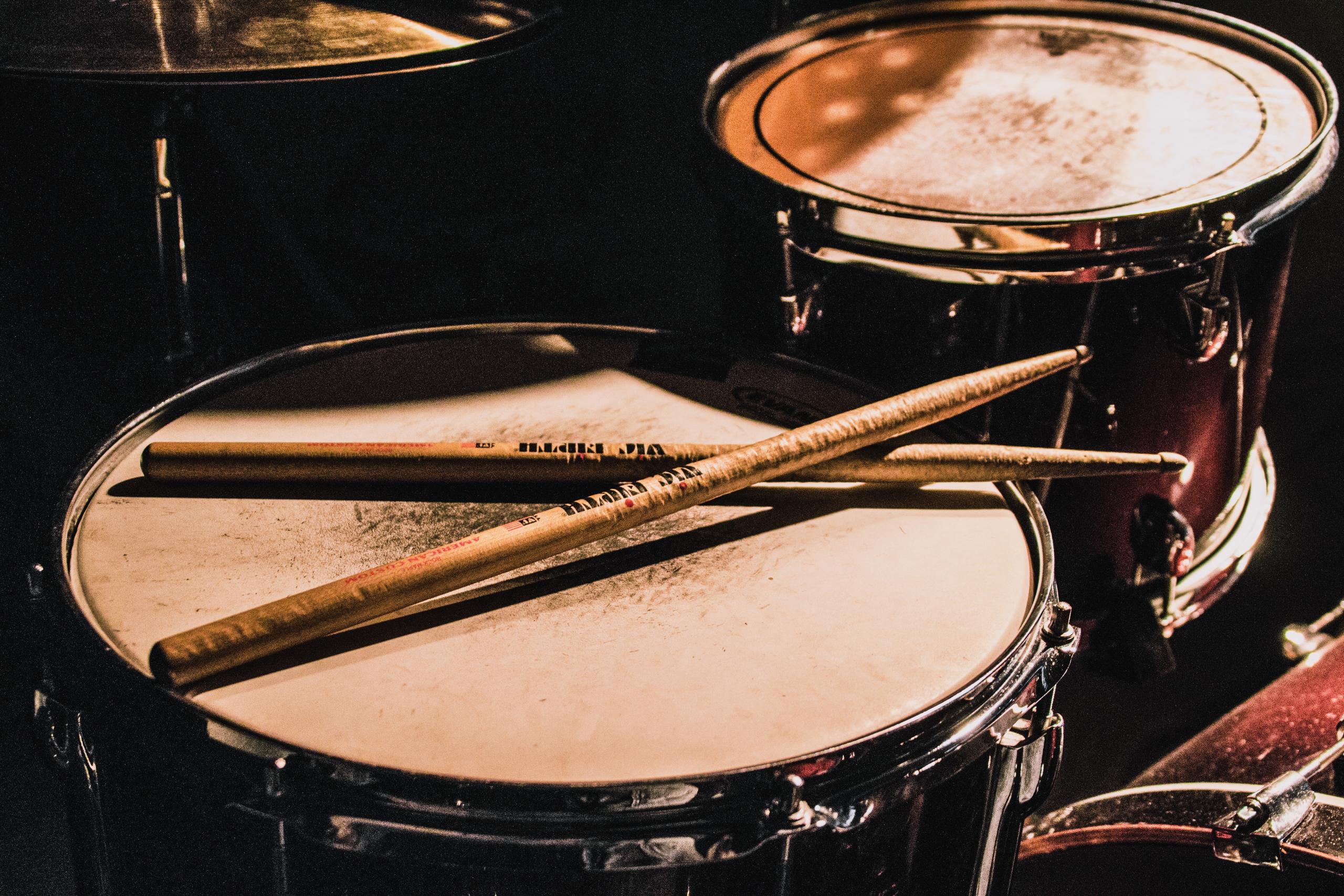 Close-up of a drum set on which two sticks are lying crossed.