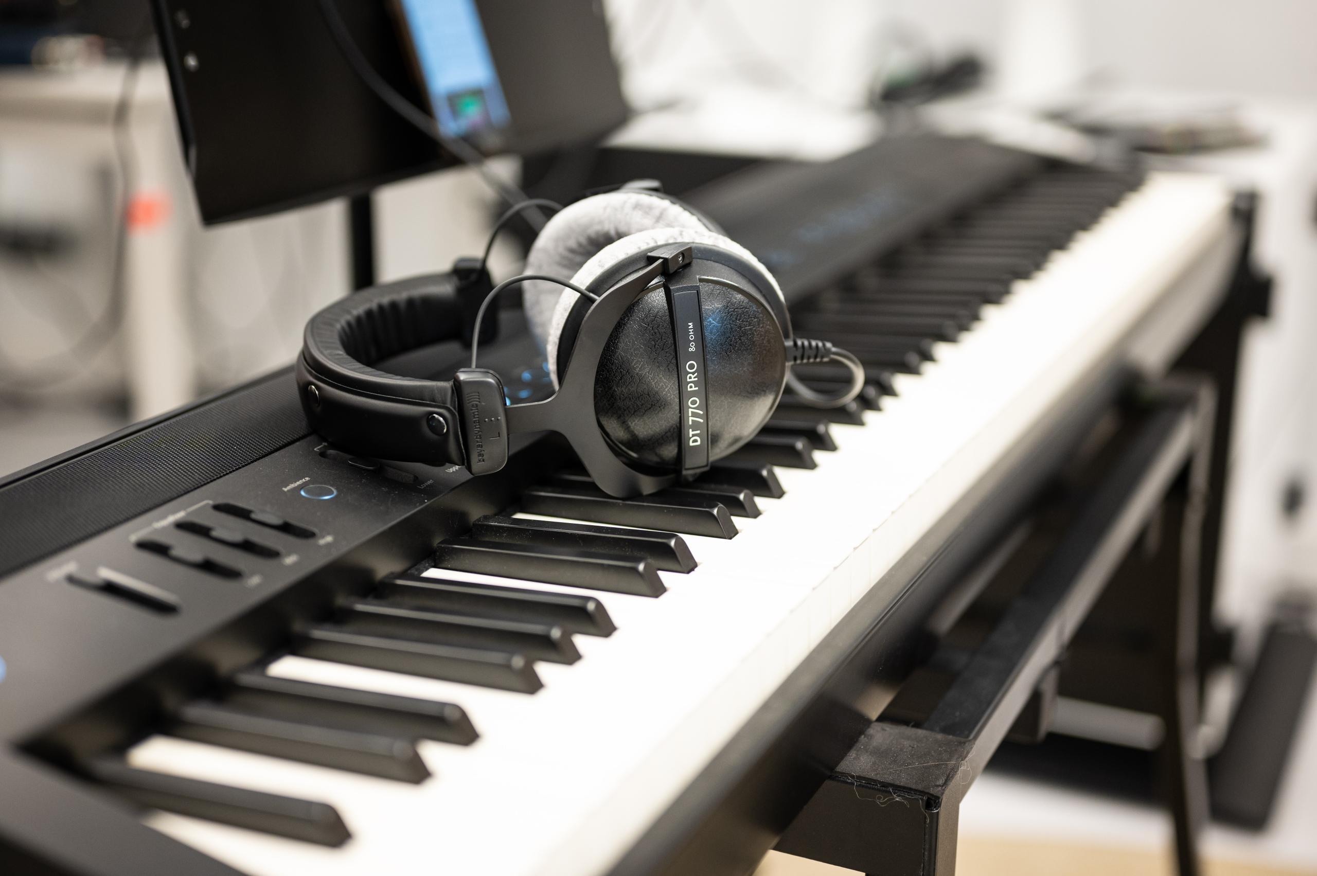 Close-up of the keys of an electronic piano, headphones resting on them