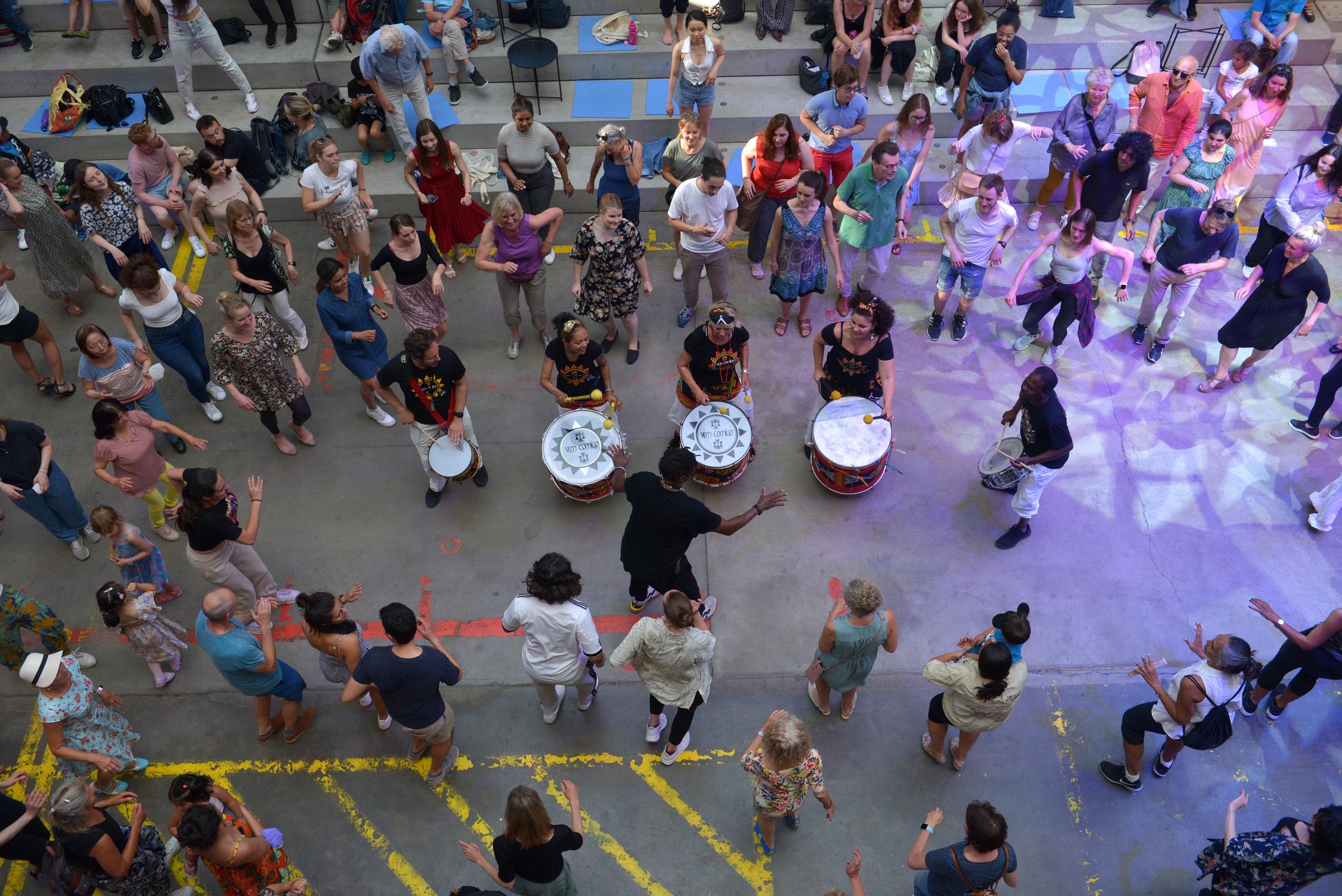 A group of people dancing around samba drummers.