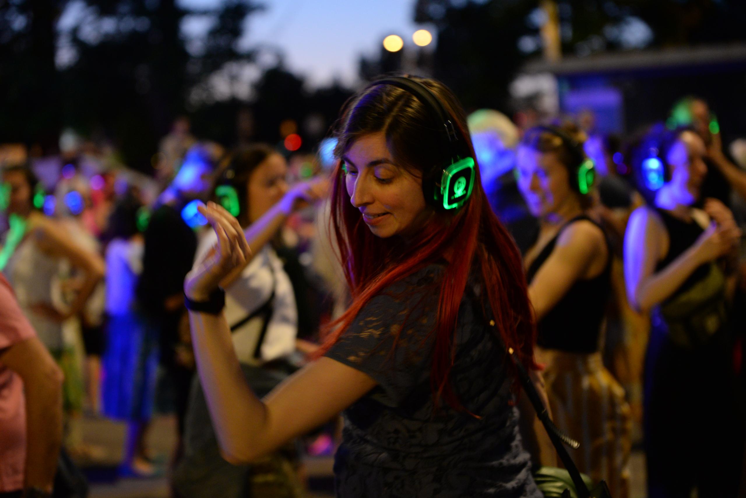 Eine junge Frau tanzt mit Kopfhörern ihren eigenen Rhythmus