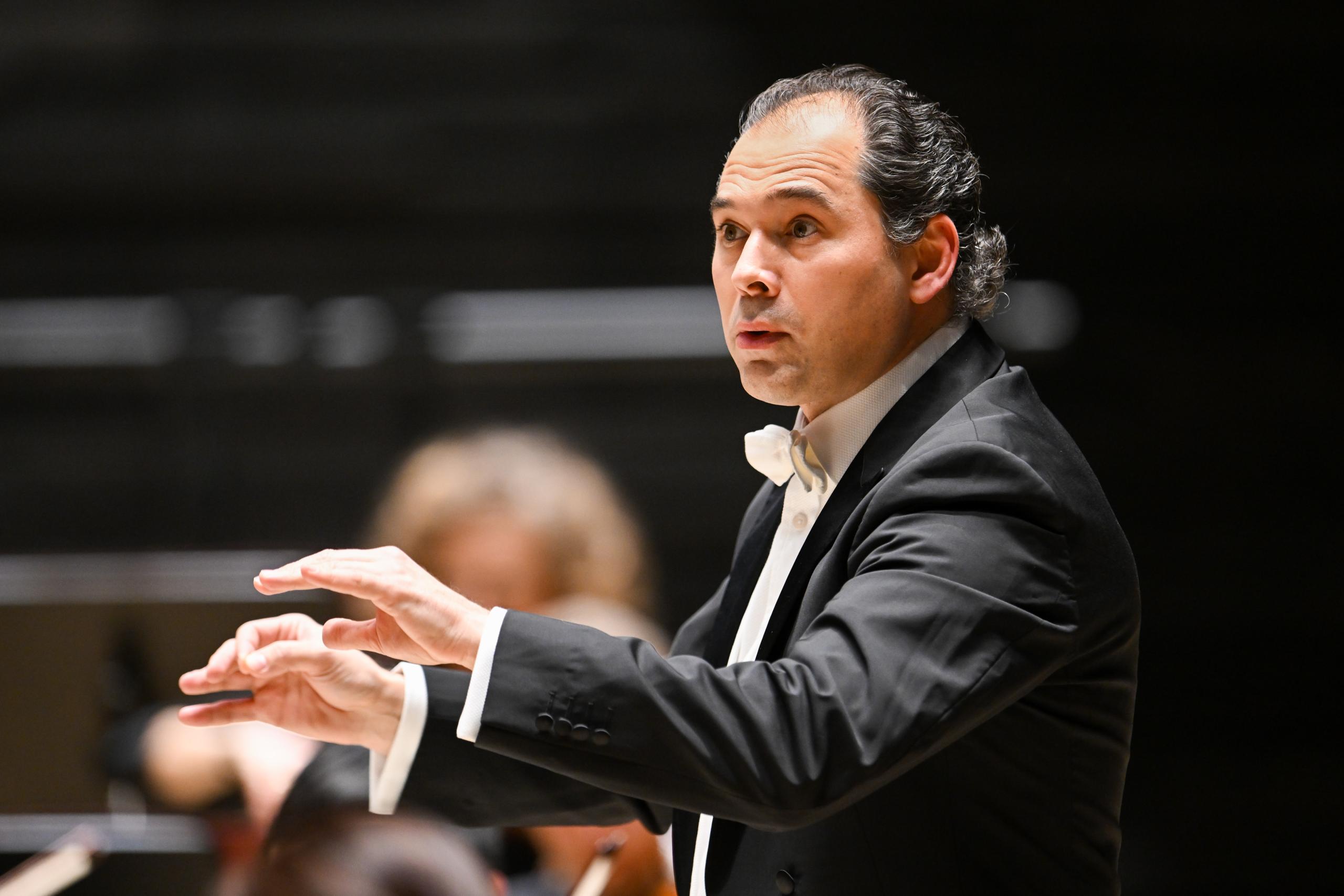 Conductor Tugan Sokhiev raised his arms while conducting