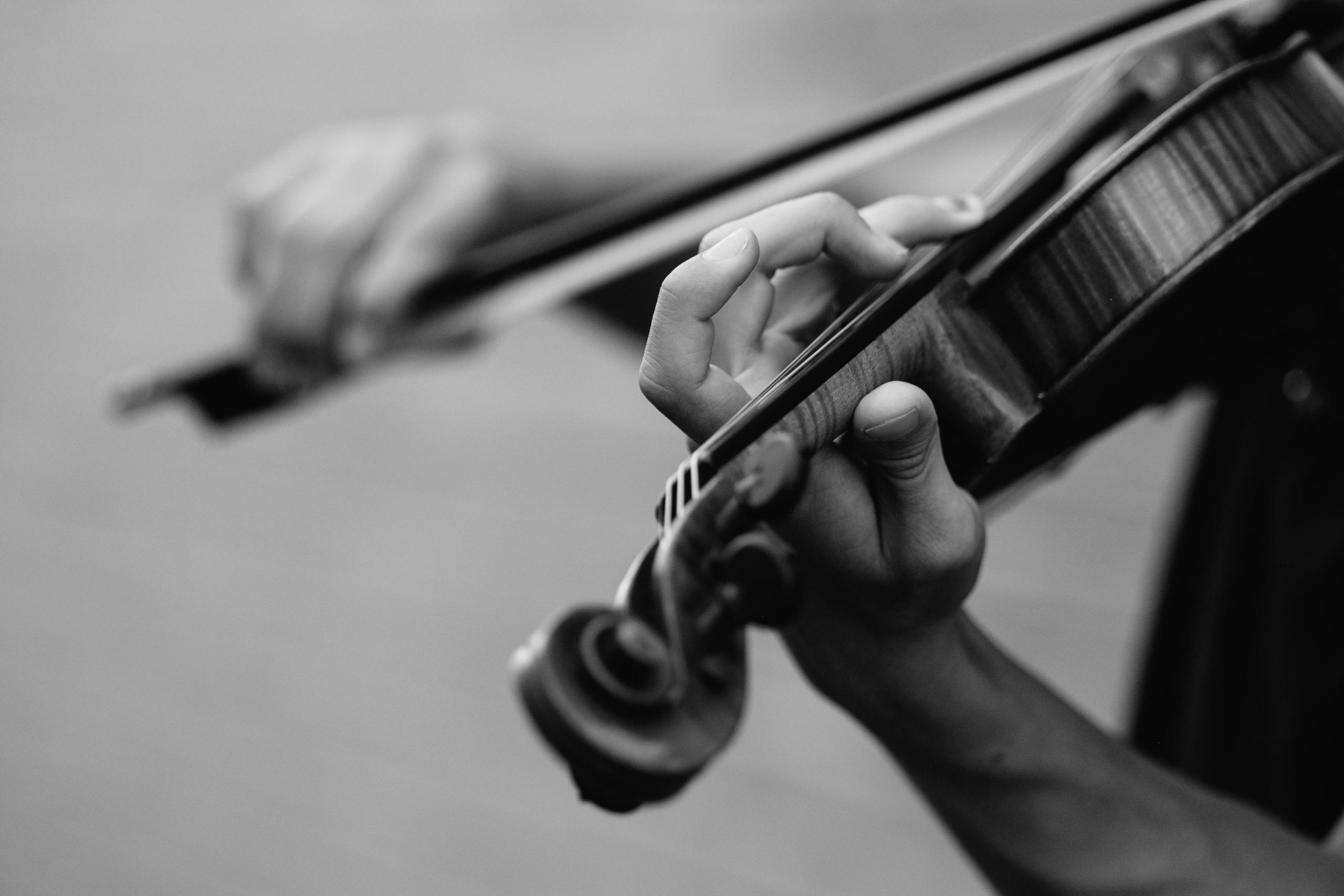 Close-up of a violin and the hand of the person playing it.