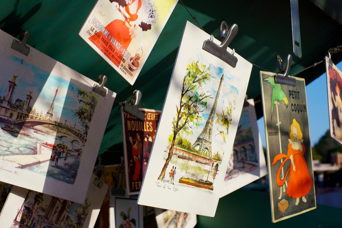 Ein Sonnenschirm, an dem Draht gespannt ist. Daran sind mit Klammern Bilder festgemacht. Sie zeigen zum Beispiel den Eiffelturm.