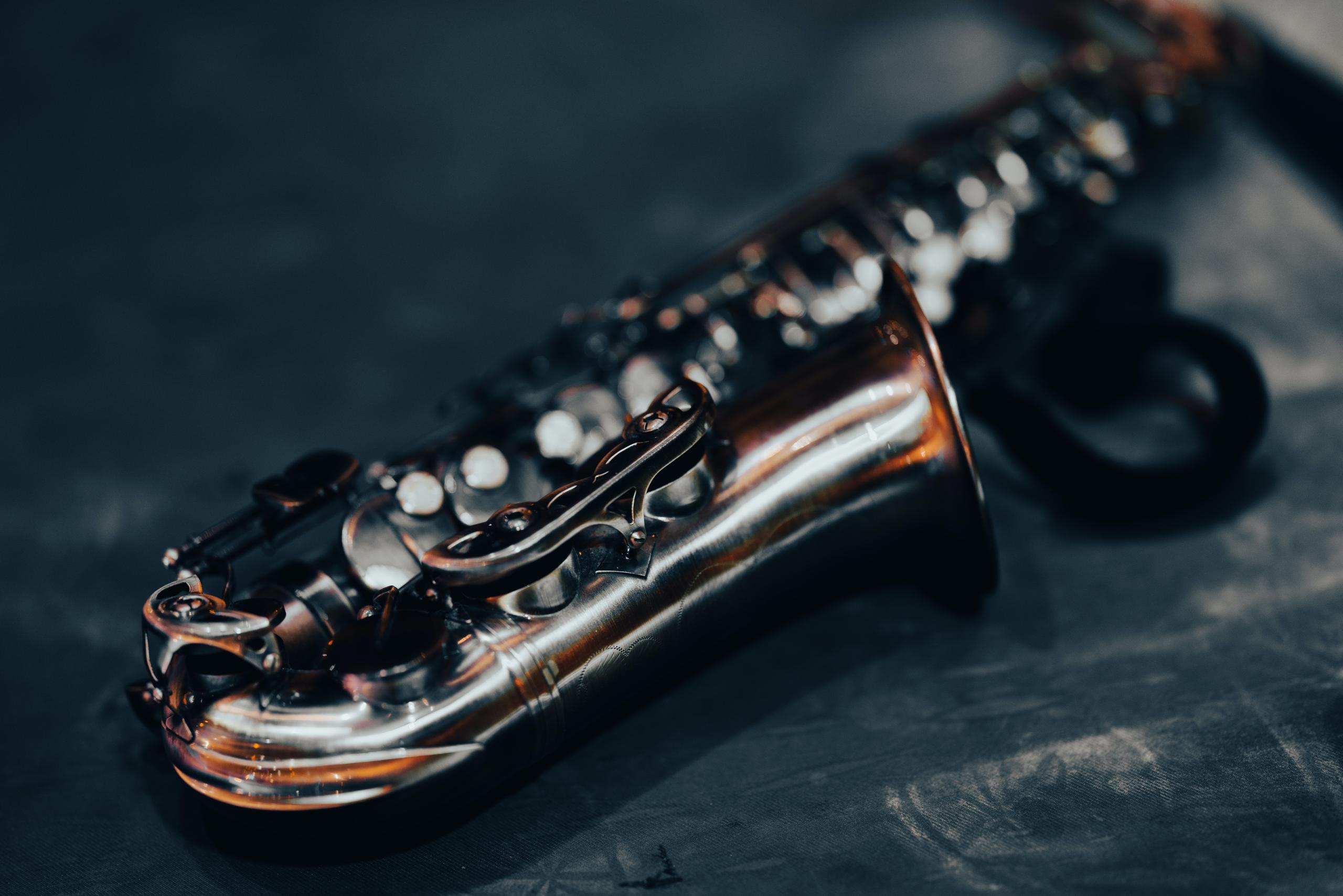 An alto saxophone lies on a dark floor