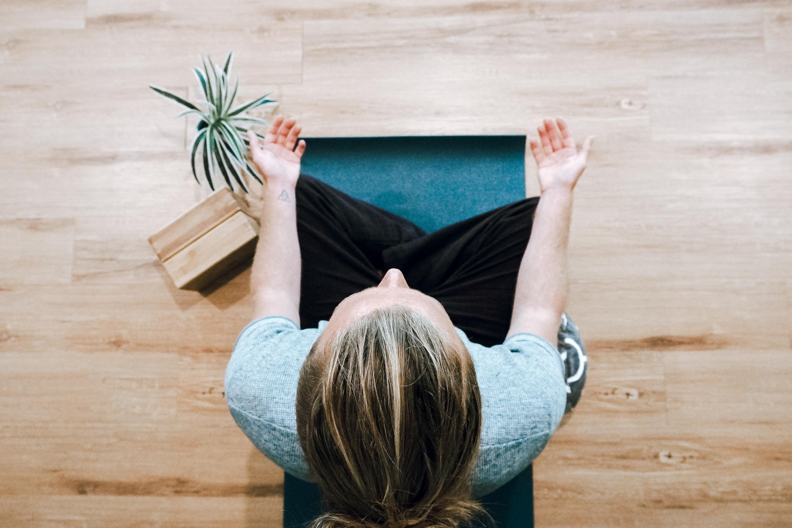 Eine Frau sitzt im Schneidersitz auf einer Yogamatte und meditiert.